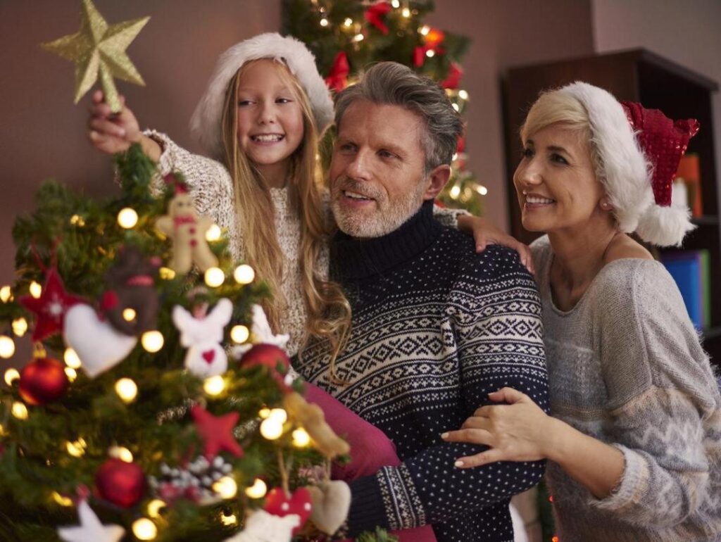 Familia poniendo el árbol de navidad en invierno