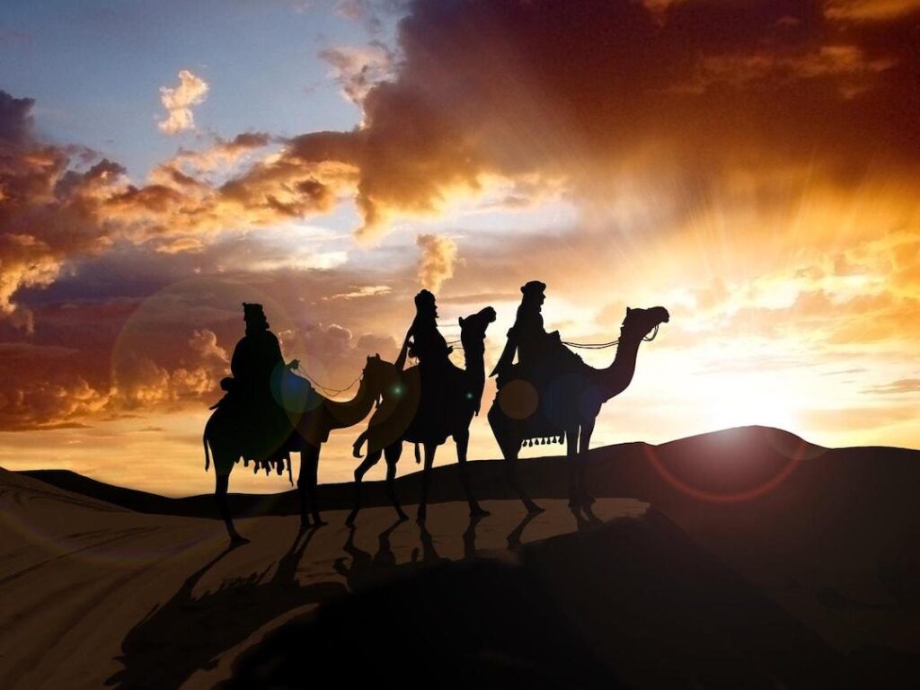 Reyes magos montando camellos en el desierto
